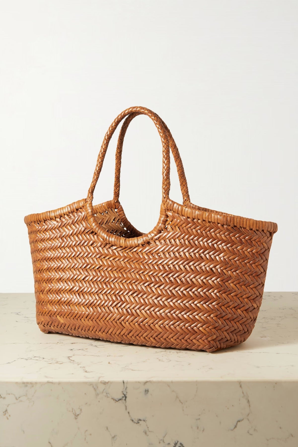 Angled view of the Dragon Diffusion Nantucket Large Tote with braided leather handles.
