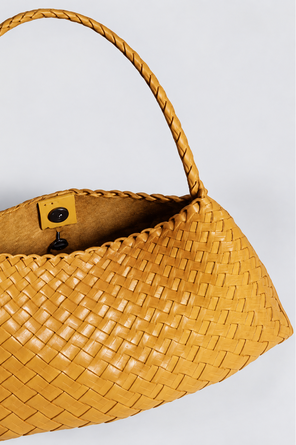 Close-up of the Rosalia Medium woven leather shoulder bag, showing its braided strap, open interior and button fastening.
