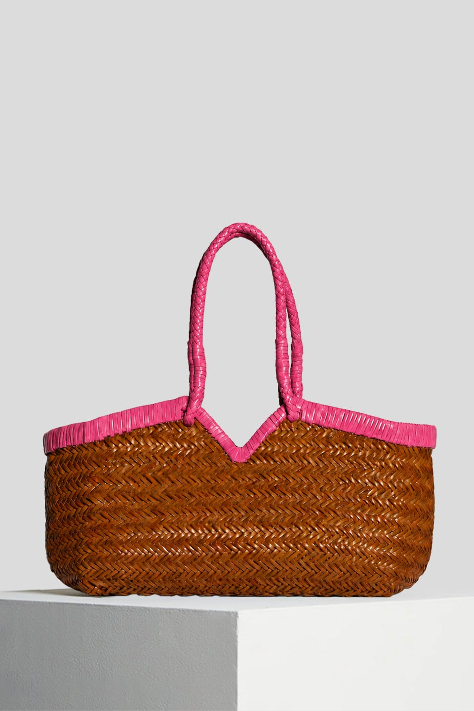 Vipera Crudelia Bicolor Cognac–Pink handwoven leather tote featuring a cognac woven leather body with bright lipstick-pink trim and braided handles.