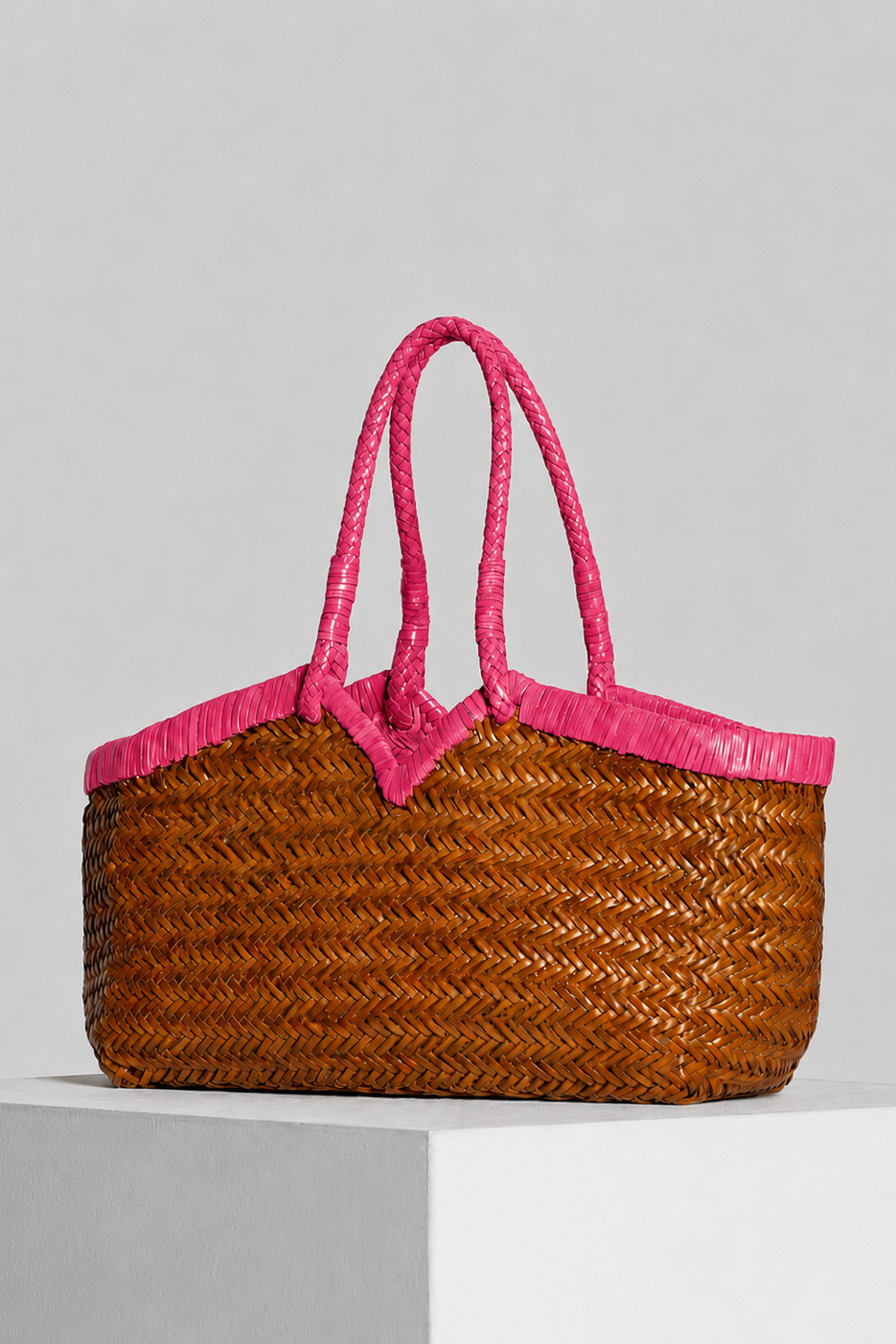 Angled view of the Vipera Crudelia Bicolor Cognac–Pink tote showcasing its handcrafted cognac leather weave with vibrant lipstick-pink accents.