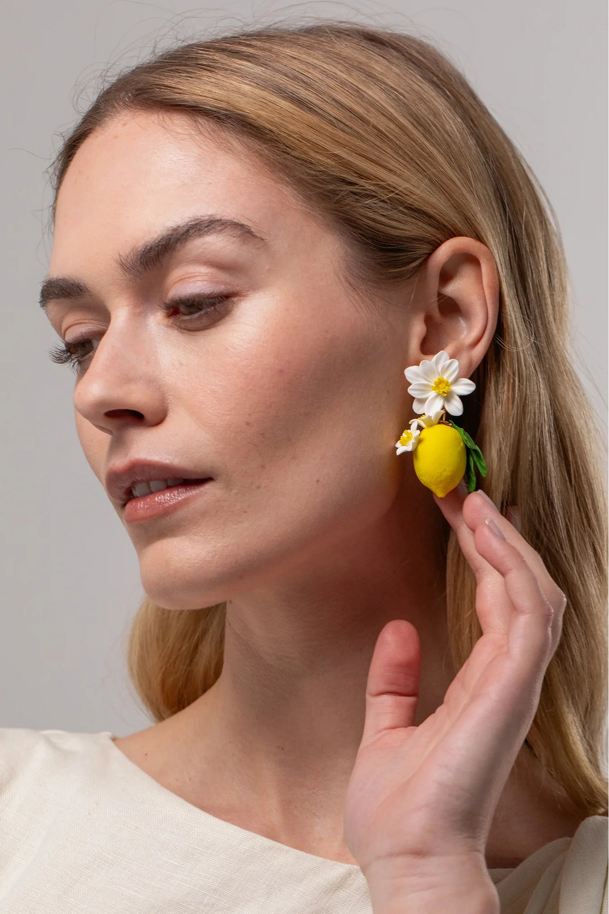 Model wearing Jennifer Behr Limoncello Earrings styled with a white blouse for an elegant summer look.