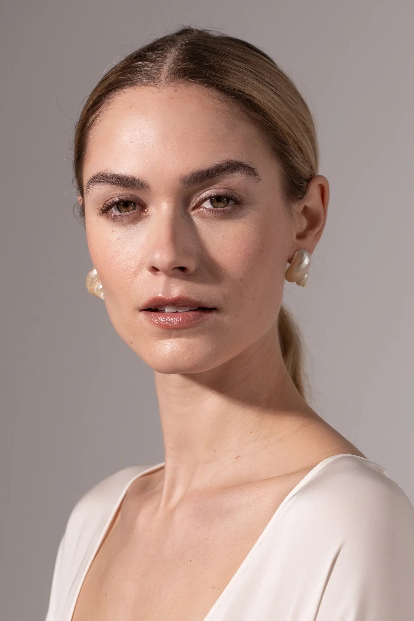 Model wearing Jennifer Behr Luca Earrings styled with an elegant ivory dress and minimalist look.