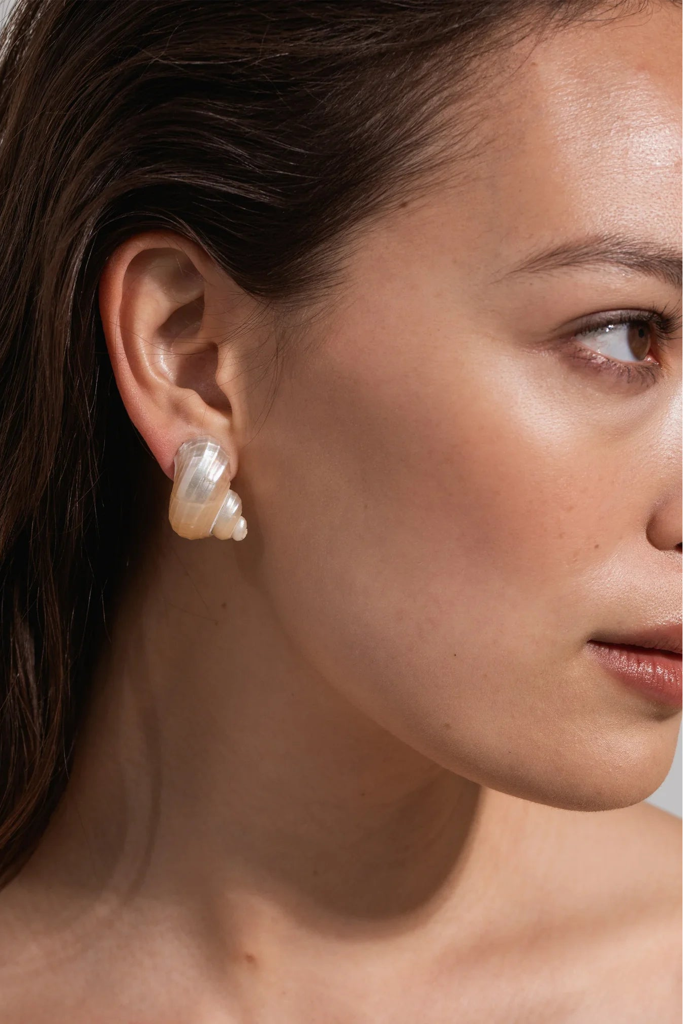 Model wearing Jennifer Behr Luca Earrings featuring natural ivory spiral shell stud earrings.