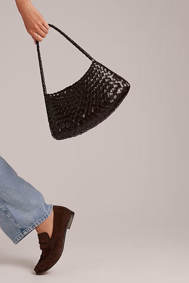 Model holding the Rosalia Shoulder Bag by its braided leather strap.