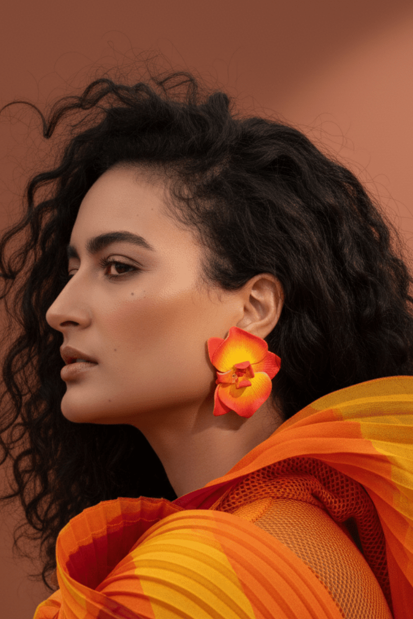 Model wearing oversized Sunset Orchid Earrings handcrafted from polymer clay in vibrant shades of red, orange, and yellow.