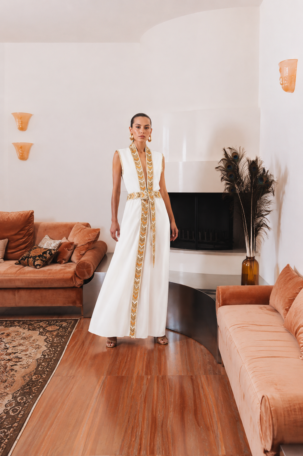 Model wearing the Natacha & Vanessa The Thalie dress in white with embroidered trim and braided belt in an elegant interior.