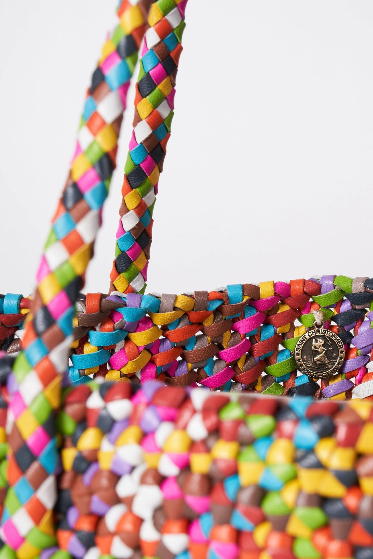 Close-up of the Octo Multi tote showing its braided handles and internal St. Christopher medal charm.