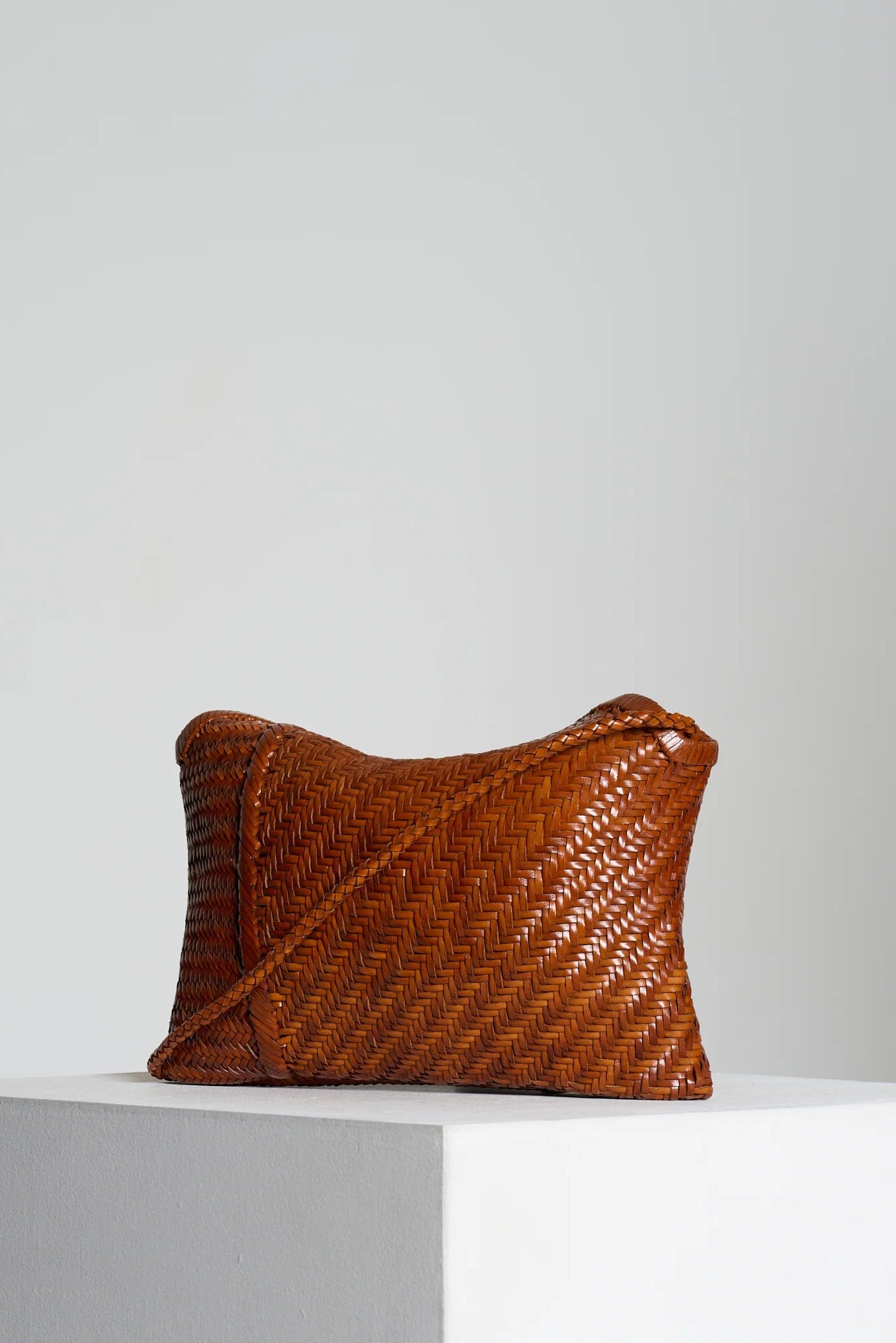 Angled view of the Vipera Pillow Cognac woven leather shoulder bag with integrated shoulder strap.