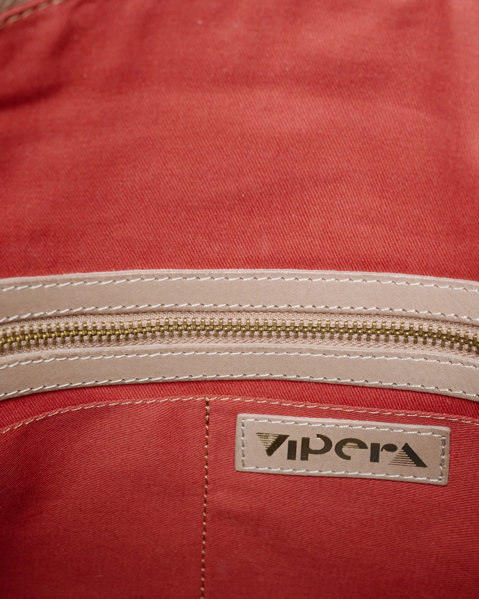 Vipera Pillow Taupe handwoven leather clutch with red interior lining and zip pocket detail.