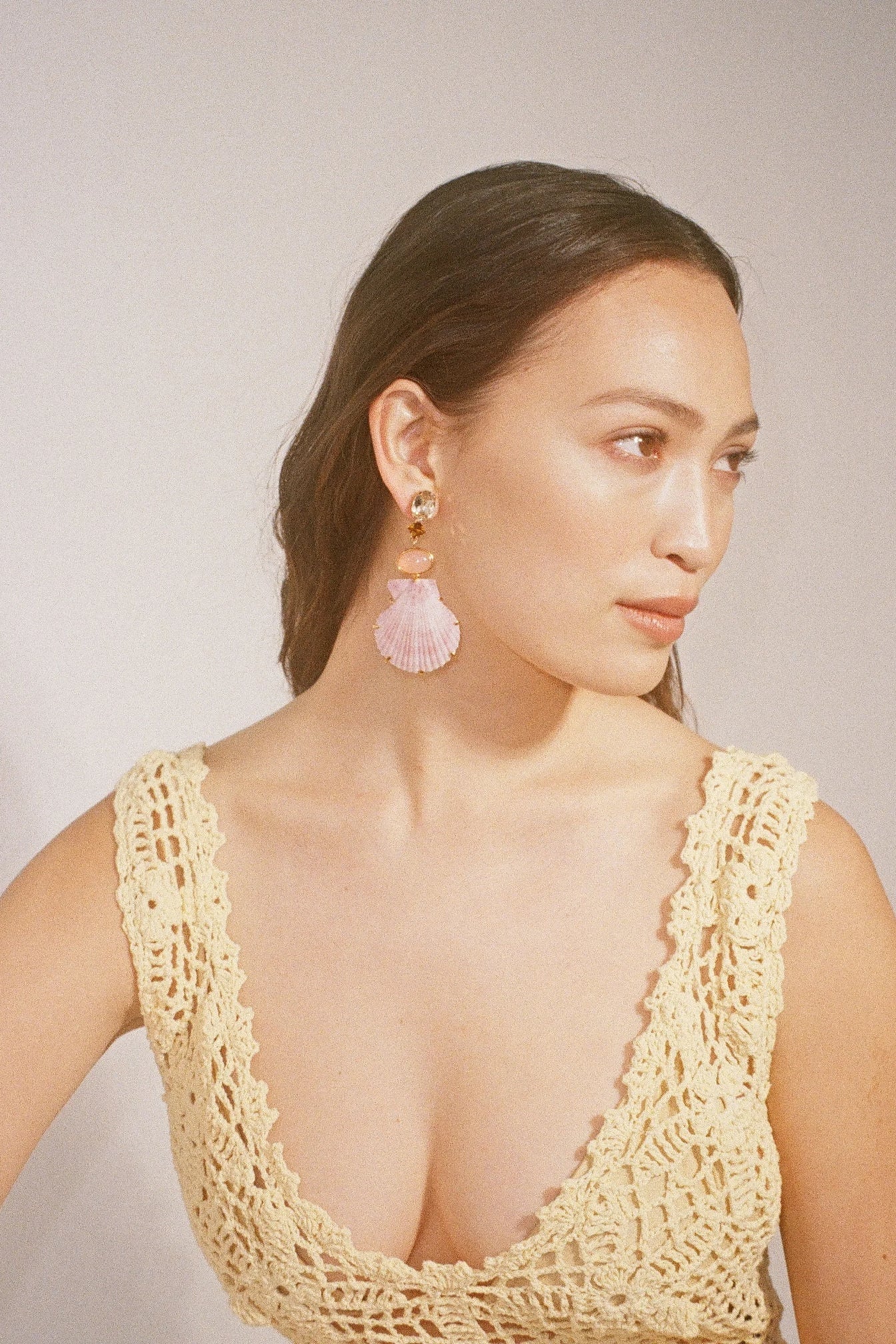 Lifestyle portrait of a model wearing Jennifer Behr Adrielle Earrings paired with a cream crochet dress for an elegant resort look.