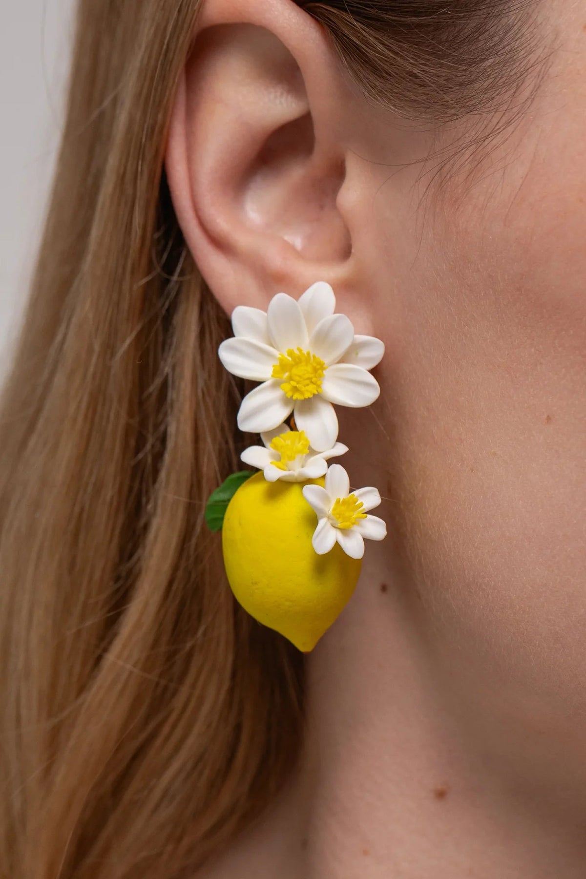 Close-up of a model wearing Jennifer Behr Limoncello Earrings showcasing the hand-sculpted lemon and floral details.