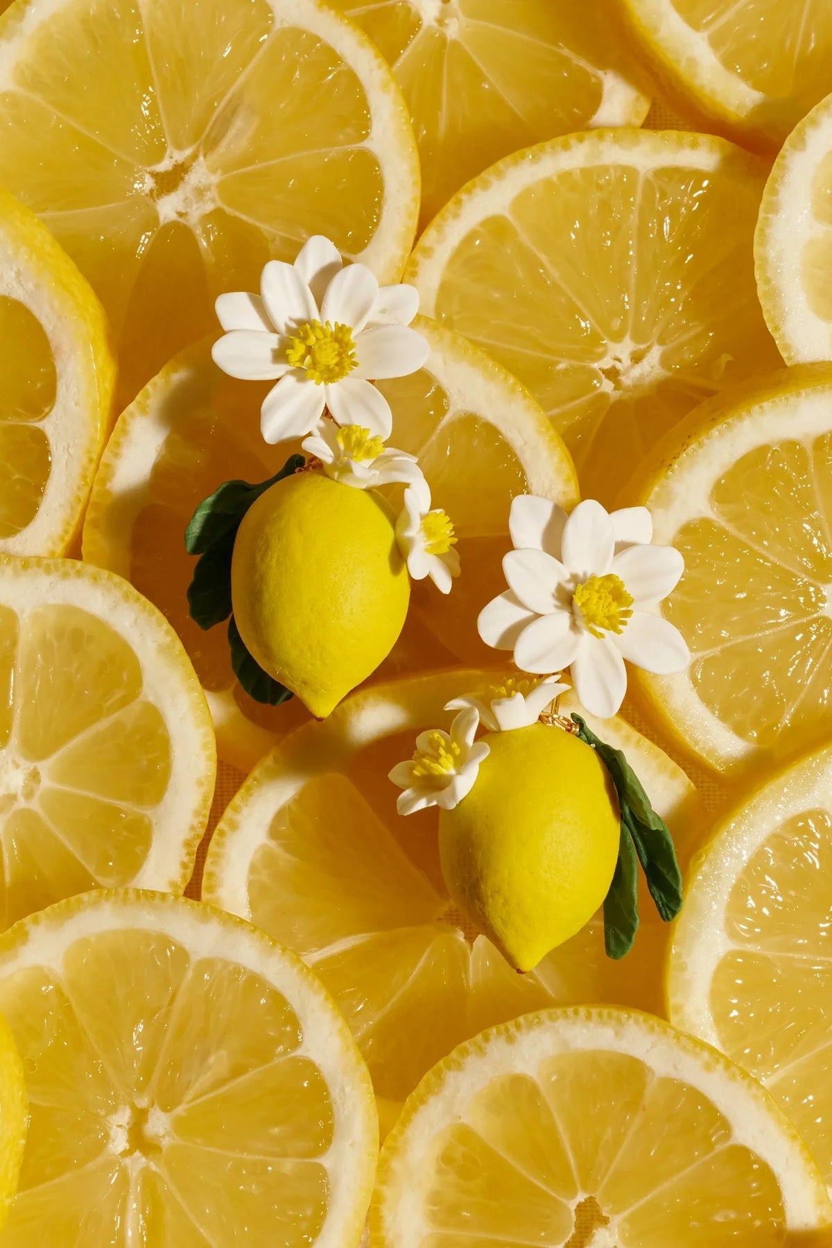 Jennifer Behr Limoncello Earrings displayed among fresh lemon slices, highlighting the handcrafted citrus-inspired design.