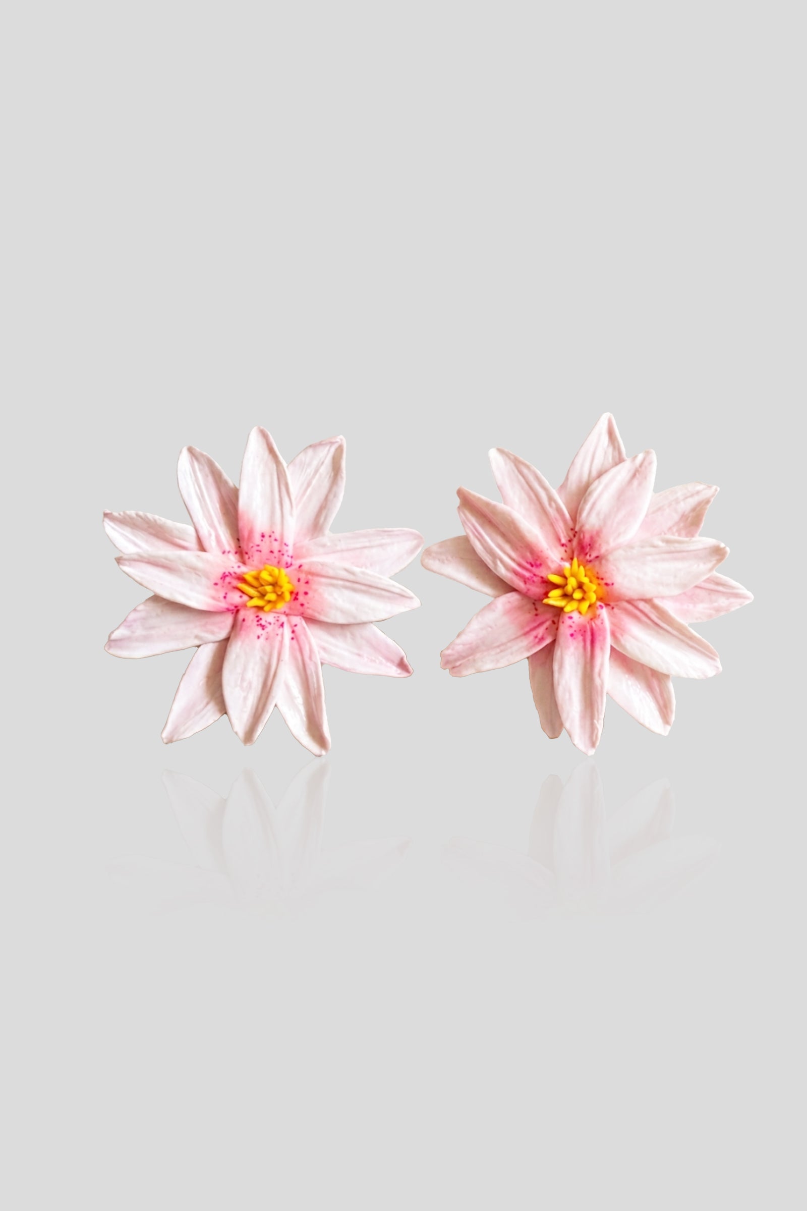 Handcrafted Lotus Rosée Earrings featuring layered blush-pink lotus blooms with rosy accents and golden yellow centers.