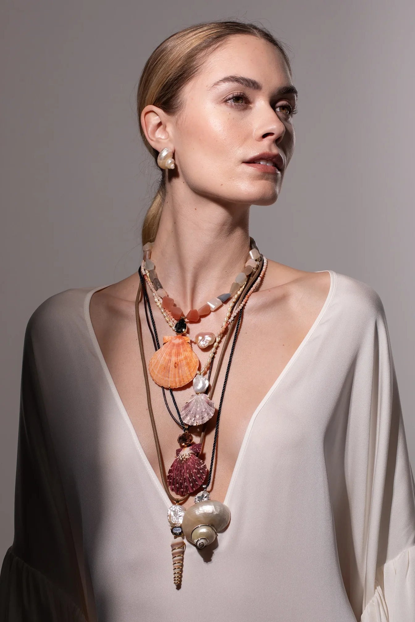 Model wearing Jennifer Behr Luca Earrings paired with layered shell necklaces for a refined coastal-inspired look.