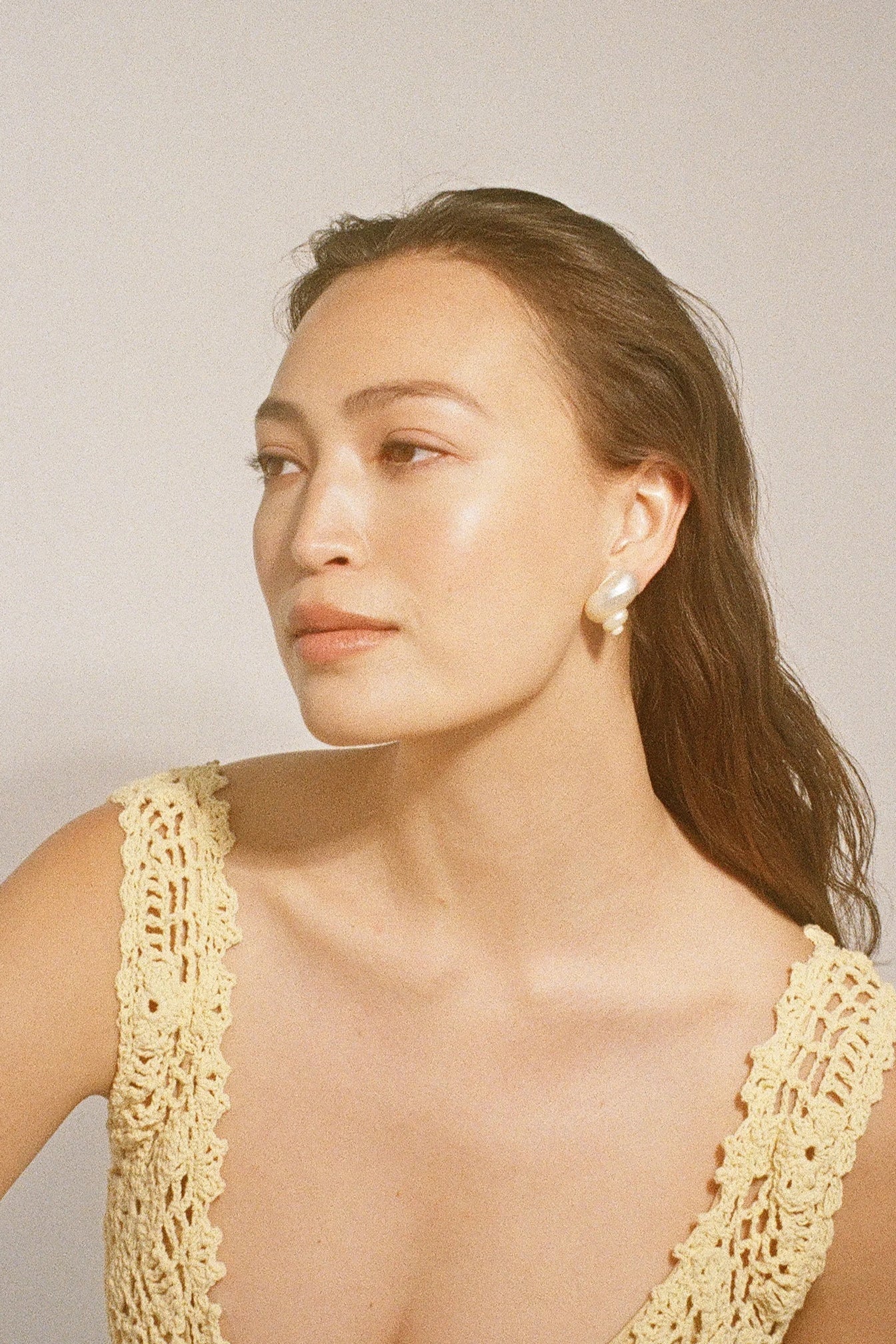 Lifestyle portrait of a model wearing Jennifer Behr Luca Earrings with natural ivory shell studs and soft resort styling.