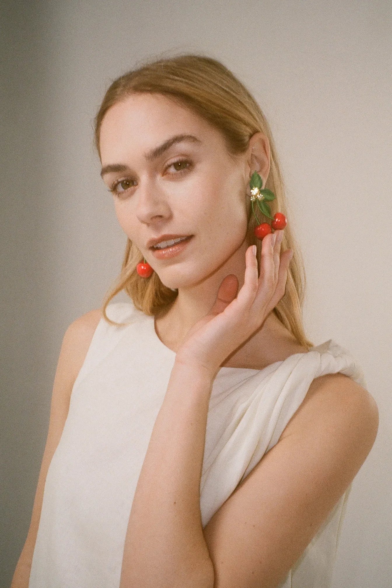 Model wearing Jennifer Behr Maraschino Earrings paired with a white dress for an elegant summer look.