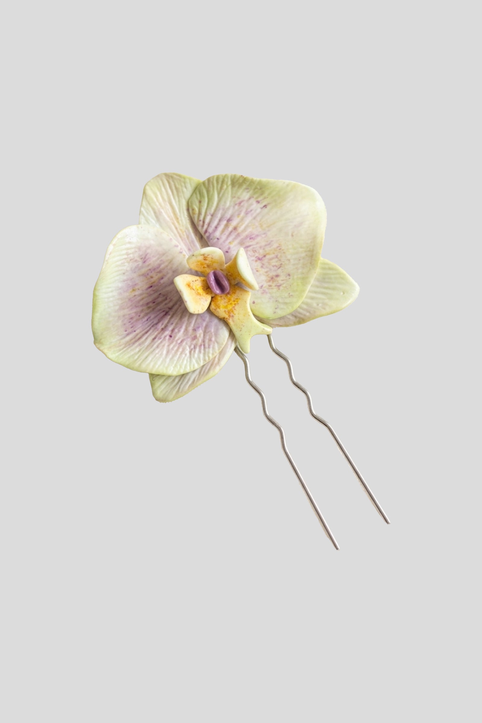 Opaline Orchid Hairpin featuring a handcrafted orchid bloom in pale green and lilac tones with a decorative hairpin attachment.