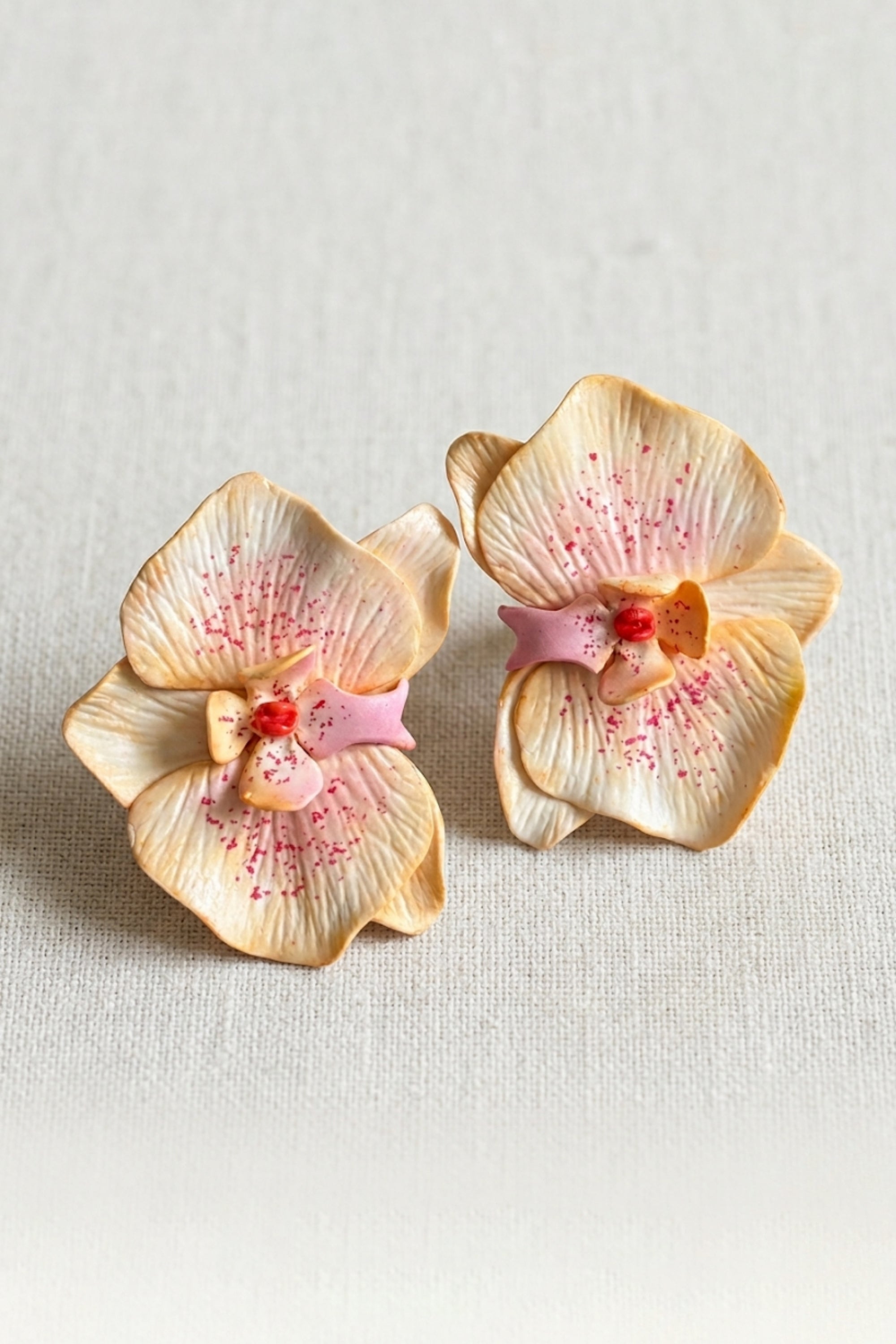 Close-up of Freckle Blush Earrings handcrafted from polymer clay with soft yellow petals, pink accents, and a romantic floral design.