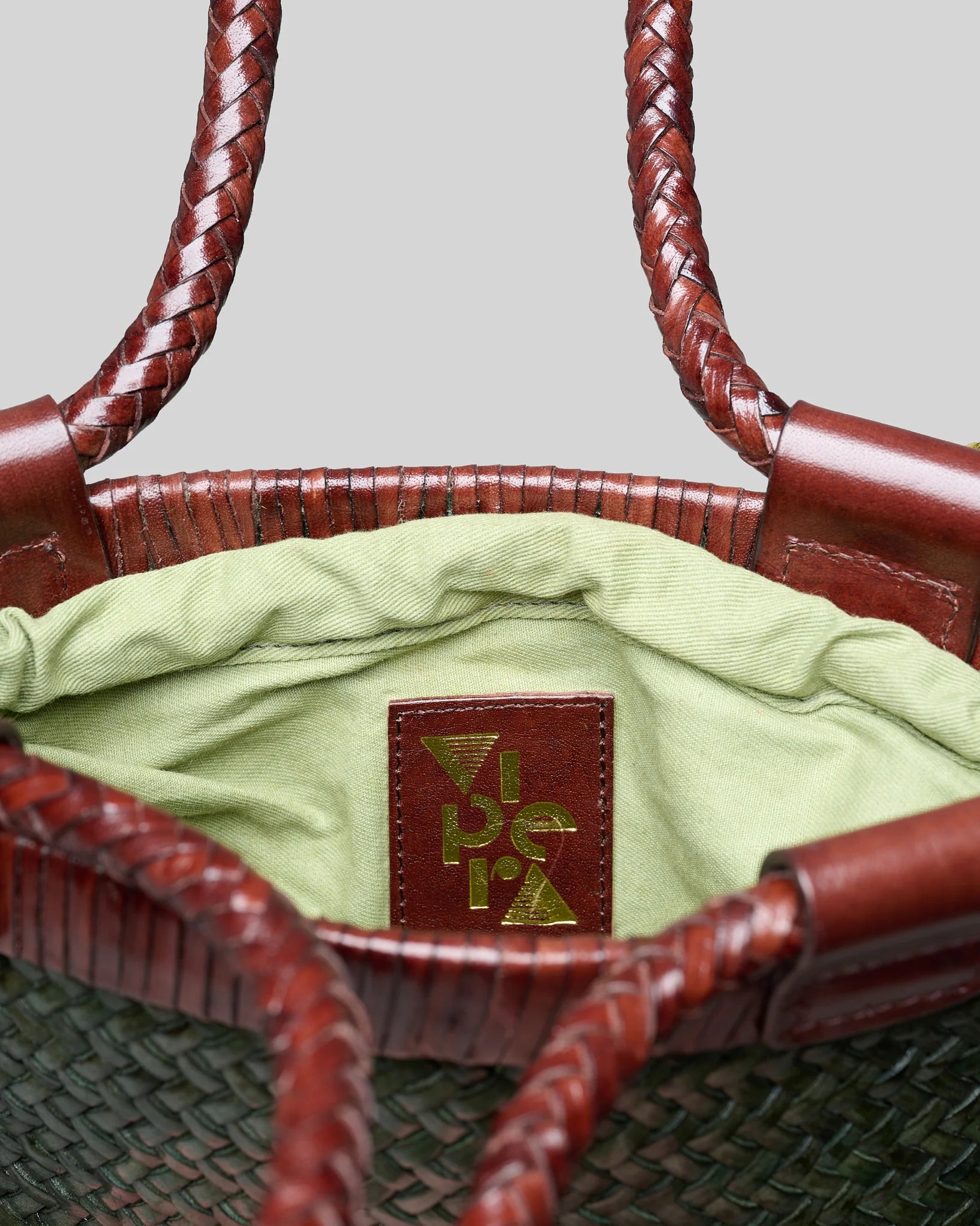 Interior view of the Vipera Gauguin Moss-Chocolate handwoven leather bag showing the removable canvas pocket and branded leather logo patch.