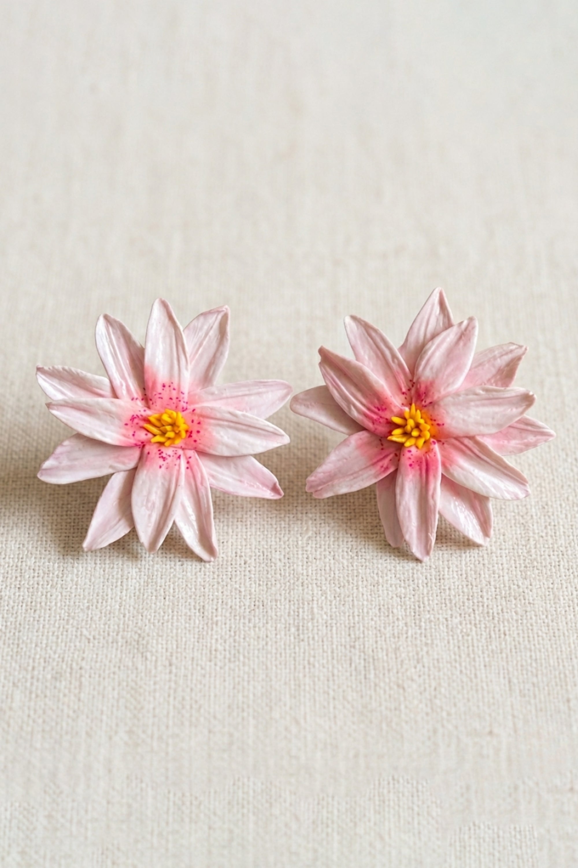 Close-up of Lotus Rosée statement earrings handcrafted from polymer clay with soft pink multi-petalled floral detailing.