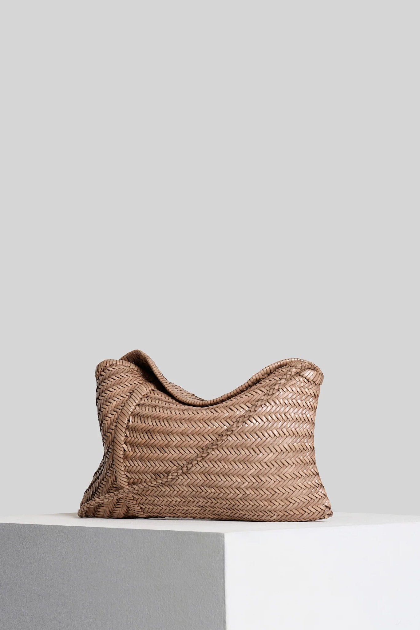 Vipera Pillow Taupe woven leather clutch with folded silhouette in taupe leather, angled view.